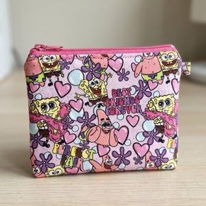 May include: A rectangular zippered pouch featuring a light pink background with a repeating pattern of SpongeBob SquarePants and Patrick Star characters, purple flowers, and pink hearts. The text BEST FRIENDS FOREVER and PERFECT PAIR is printed.
