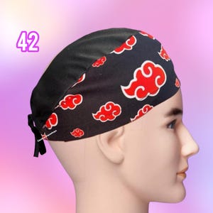May include: Black scrub cap with a pattern of red clouds on a black background. The cap has a black tie in the back. The number "42" is printed in purple on the left side of the image.
