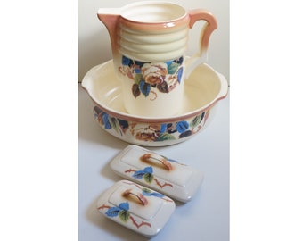 May include: A vintage bathroom set with a pitcher, bowl, and two soap dishes. The set is decorated with a floral pattern in shades of brown, blue, and white.
