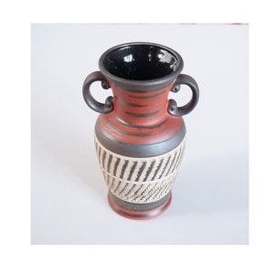 May include: A small, red and black ceramic vase with two handles. The vase has a geometric pattern and a black glazed interior.