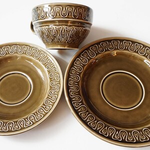 May include: A set of three green ceramic teacups and saucers with a white geometric pattern. The cups and saucers have a glossy finish.