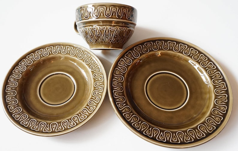 May include: A set of three green ceramic teacups and saucers with a white geometric pattern. The cups and saucers have a glossy finish.