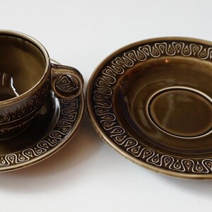 May include: A green teacup and saucer set with a brown and white geometric pattern.