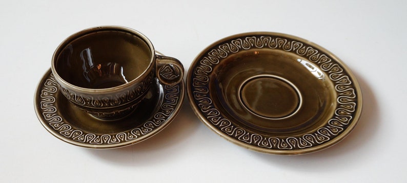 May include: A green teacup and saucer set with a brown and white geometric pattern.