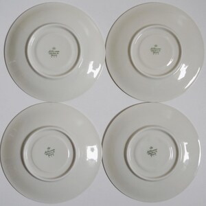 May include: Four white ceramic saucers with a green printed logo that reads "Alt Wiener Porzellan" on the bottom.