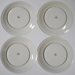 May include: Four white ceramic dinner plates with a green and gold logo that reads "Jobst Germany" on the bottom.