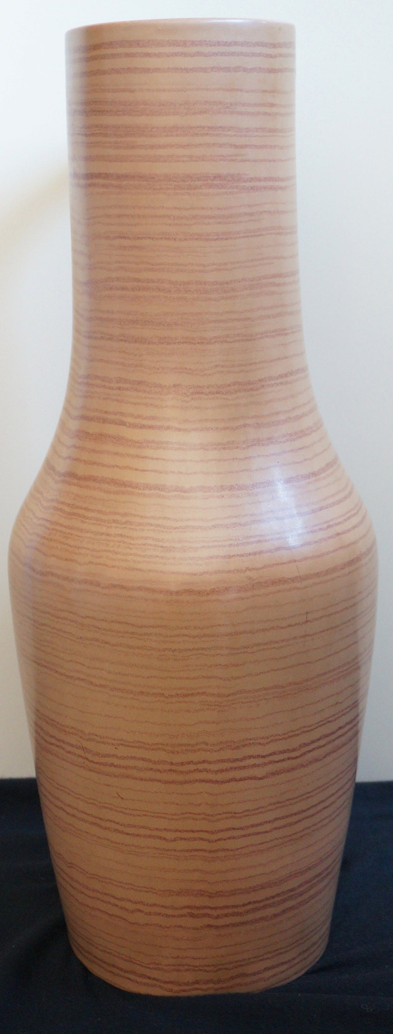 Puede incluir: Un jarr&oacute;n alto de cer&aacute;mica marr&oacute;n claro con un patr&oacute;n de veta de madera. El jarr&oacute;n tiene una base ancha y un cuello estrecho.