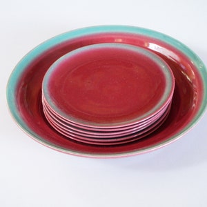 May include: A set of red and green ceramic plates. The plates are stacked on top of each other, with the largest plate at the bottom and the smallest plate at the top.