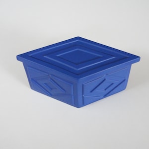 Op de afbeelding: Een blauwe keramische doos met een geometrisch ontwerp op de deksel en zijkanten. De doos is vierkant en heeft een deksel dat perfect aansluit.