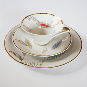 Könnte beinhalten: Ein weißes Tee-Set mit goldenen Rand und einem stilisierten Blumendesign in Blau-, Gelb- und Rottönen.