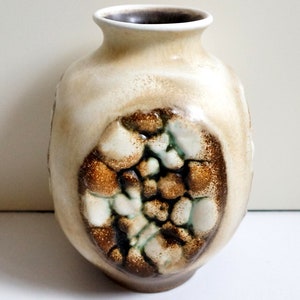 Op de afbeelding: Een beige keramische vaas met een textuuroppervlak en een donkerbruin interieur. De vaas heeft een centraal ontwerp van bruine, witte en groene texturele elementen. De vaas is ongeveer 20 cm hoog.