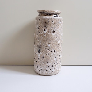 Może przedstawiać: Brązowy i biały ceramiczny wazon z pstrokatą glazurą. Wazon ma cylindryczny kształt i zaokrągloną podstawę.