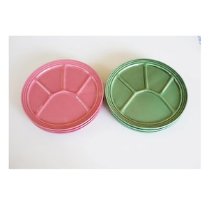 Op de afbeelding: Twee ronde, verdeelde serveerschalen. De ene is een stapel roze borden en de andere een stapel groene borden. Elke schaal heeft vijf secties. De borden zijn gemaakt van keramiek en hebben een glanzende afwerking. De borden staan op een witte achtergrond.