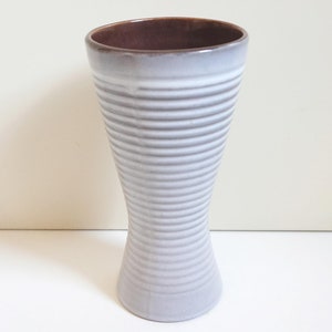 May include: A white ceramic vase with brown glaze on the rim. The vase has a ribbed design and a flared opening.
