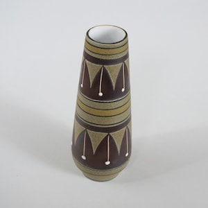 May include: A brown ceramic vase with a geometric pattern in shades of brown, white, and yellow. The vase has a narrow opening and a wide base.