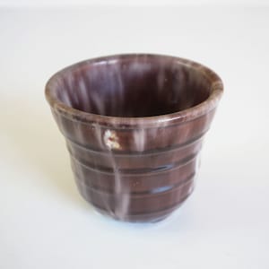 Op de afbeelding: Een kleine, bruine keramische pot met witte glazuur. De pot heeft een geribbeld ontwerp en is perfect voor kleine planten.