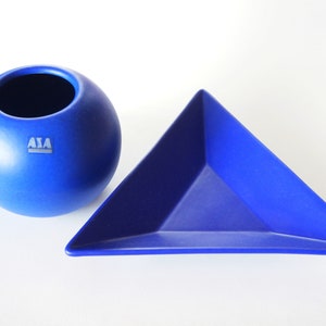 Könnte beinhalten: Ein Set aus zwei blauen Keramik-Schalen. Eine ist eine runde Schale mit einer kleinen Öffnung oben und die andere ist eine dreieckige Schale. Die Schale hat den Schriftzug "ASA" auf der Seite.