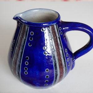 May include: A blue ceramic jug with white and brown stripes and a white and black polka dot pattern.