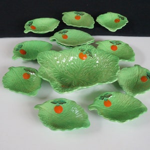 May include: A set of 10 green ceramic serving dishes shaped like lettuce leaves with a red tomato design. The dishes are perfect for serving snacks, dips, or appetizers.