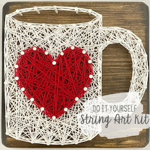 May include: DIY string art kit featuring a coffee mug with a red heart in the center. The kit includes all the materials needed to create the artwork, including string, nails, and a wooden base.  Do It Yourself String Art Kit.