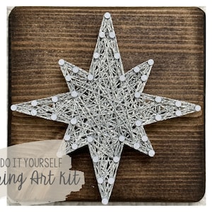 May include: DIY string art kit featuring a silver star design on a wooden base. The kit includes all the materials needed to create the art, including string, nails, and a wooden base.