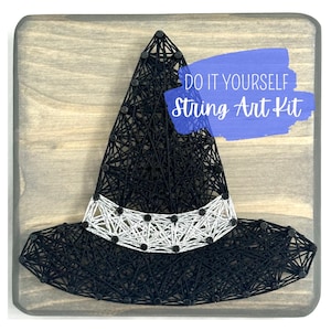 May include: A black string art witch hat with a white band and black accents, mounted on a wooden board. The words "DO IT YOURSELF String Art Kit" are displayed in a blue banner.