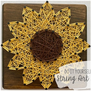 May include: DIY string art kit featuring a sunflower design with yellow and brown string on a wooden base. The kit includes all the materials needed to create the artwork.  "Do It Yourself String Art Kit" is written on the base.