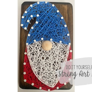 May include: DIY string art kit featuring a gnome design. The gnome's hat is blue, the beard is white, and the bottom is red, all made with string on a wooden board. The text "DO IT YOURSELF String Art Kit" is visible.