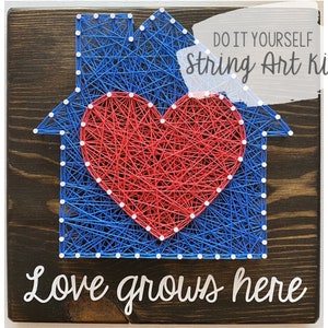 May include: DIY string art kit featuring a house with a red heart inside. The text "Love grows here" is written below the house.