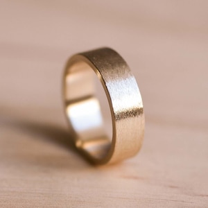 May include: A simple gold band ring with a brushed finish.
