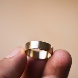 May include: A simple gold wedding band with a brushed finish.