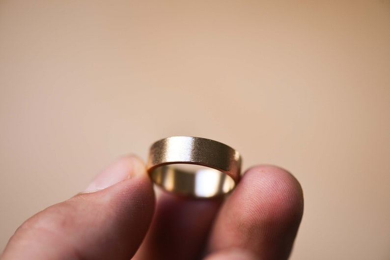May include: A simple gold wedding band with a brushed finish.