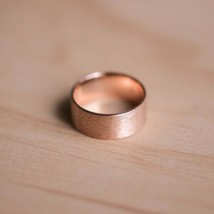 May include: A rose gold ring with a brushed finish.