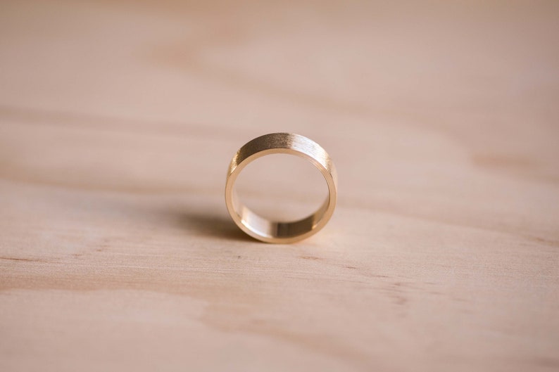 May include: A simple gold band ring with a brushed finish.
