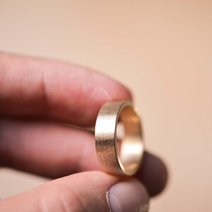 May include: A gold wedding band with a brushed finish.