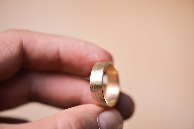 May include: A gold wedding band with a brushed finish.