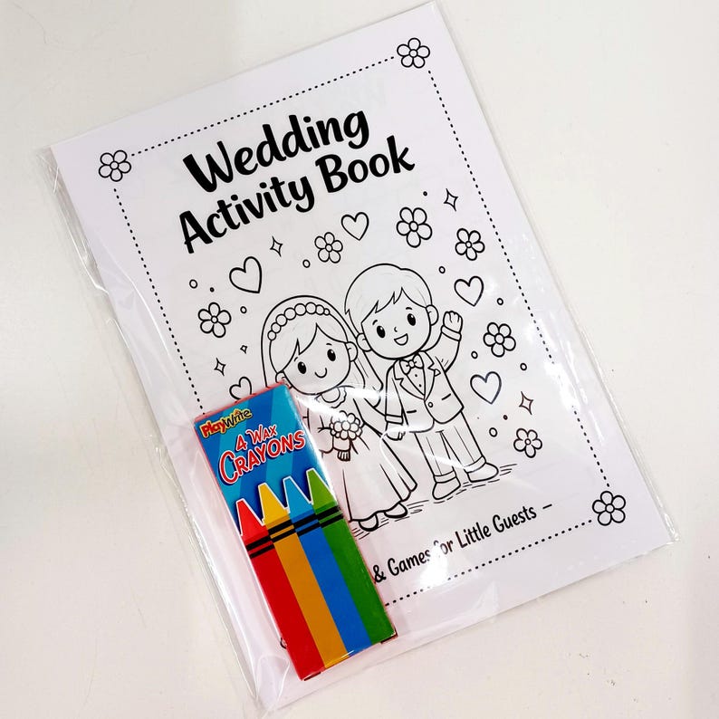 May include: A white wedding activity book with black line art of a bride and groom, flowers, and hearts, featuring the text Wedding Activity Book and Games for Little Guests. A small box of four wax crayons in red, yellow, blue, and green is included.