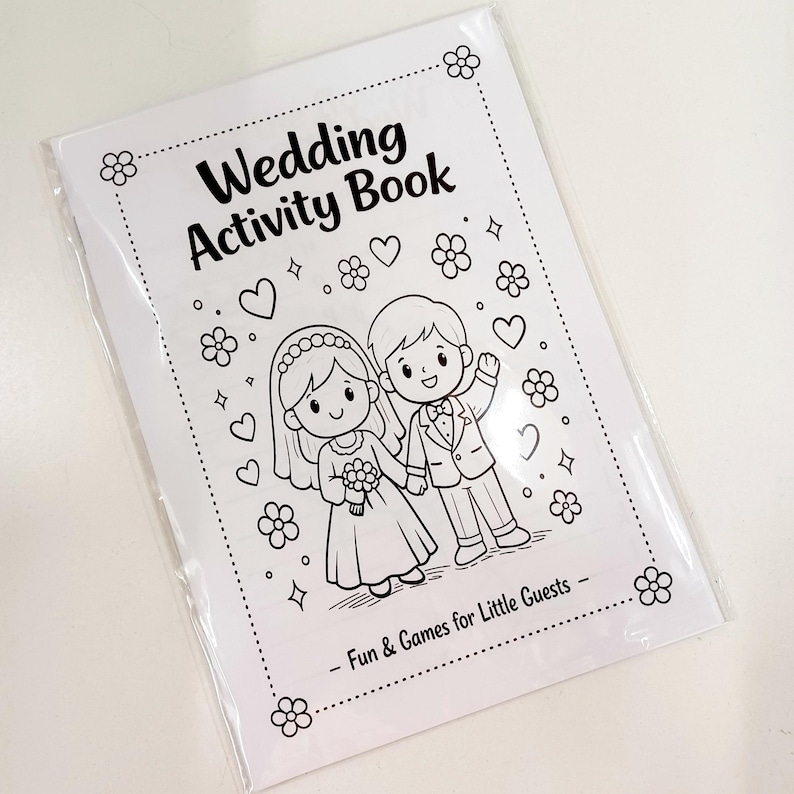 May include: A white paper wedding activity book in a clear plastic sleeve. The cover features black line art of a bride and groom surrounded by hearts, flowers, and stars. The text reads Wedding Activity Book and Fun & Games for Little Guests.