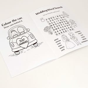 May include: An open activity book with black and white line art. The left page features a car with a Just Married heart sign and text Colour the car. Draw cans behind it. The right page shows a Wedding Word Search with illustrations of a couple.