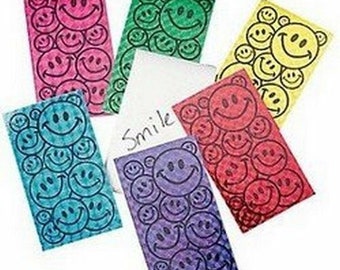 May include: Six colorful cards with a repeating pattern of smiley faces. The cards are in shades of pink, green, yellow, red, blue, and purple. The word "Smile" is written on a white card.