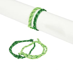 May include: Two green and light green rope bracelets with knots. The bracelets are made of braided rope.