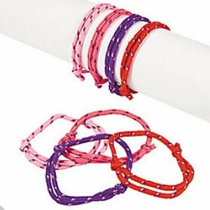 May include: A set of colourful friendship bracelets made of woven pink, red and purple string. The bracelets are tied together in a bundle.