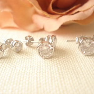May include: Three pairs of silver stud earrings with clear round cubic zirconia stones.