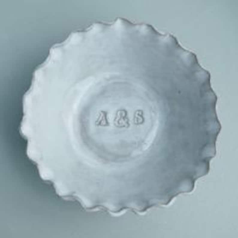 May include: White ceramic bowl with a scalloped edge and the initials "A & S" embossed on the bottom.