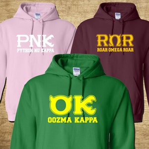 May include: Three hooded sweatshirts in different colors with Greek letter logos. The pink sweatshirt has a white logo that says "PNK PYTHON NU KAPPA". The maroon sweatshirt has a gold logo that says "ROR ROAR OMEGA ROAR". The green sweatshirt has a yellow logo that says "OK OOZMA KAPPA".