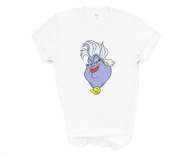 May include: White t-shirt with a cartoon image of Ursula from The Little Mermaid. Ursula is a purple sea witch with white hair and a mischievous expression.