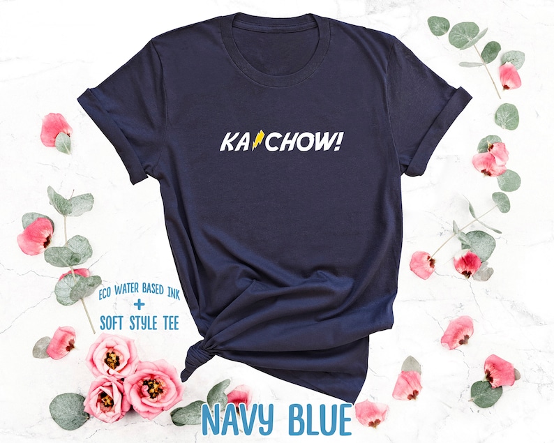 Op de afbeelding: Donkerblauw t-shirt met een gele bliksem en de tekst "KACHOW!" gedrukt op de voorkant. Het shirt is gemaakt van een zacht, comfortabel materiaal.