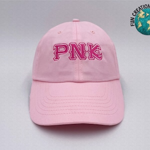 May include: A pink baseball cap with the word "PNK" embroidered in pink on the front.