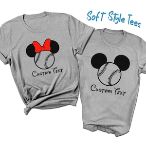 May include: Two grey t-shirts with a baseball and Mickey Mouse ears design. The shirt on the left has a red bow on the Mickey Mouse ears. Both shirts have the text "Custom Text" printed on them.