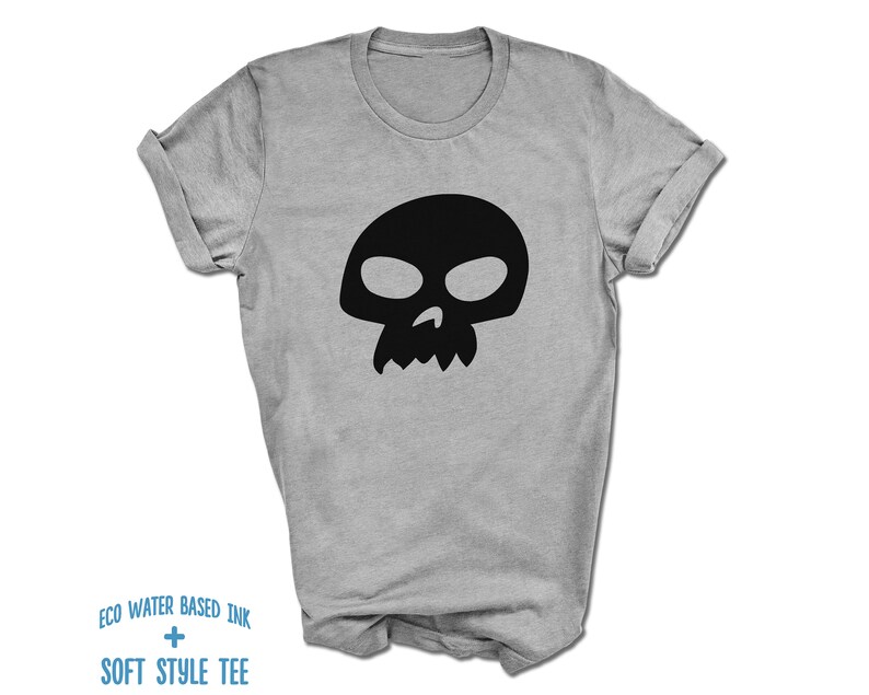 Pu&ograve; includere: Una maglietta grigia con una grafica di teschio nero. Il testo "ECO WATER BASED INK + SOFT STYLE TEE" &egrave; stampato sul fondo della maglietta.